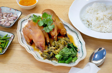Stewed pork leg (Kaki) with Chinese spices in white dish and rice on wooden background