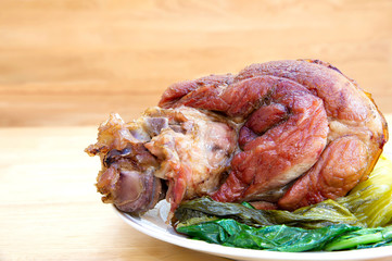 Stewed leg pork without fat with vegetables in white dish on brown wooden table