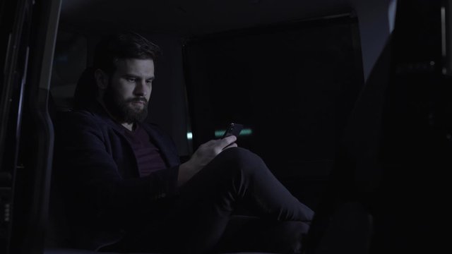 Young man check his mobile phone before trip at vip van shuttle