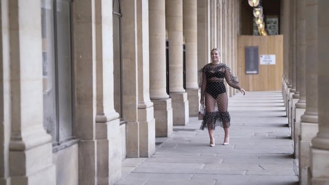 Girl in sexy extravagant dress and black underwear walking near the Louvre museum in Paris, Franc. Action. Amazing plus size model posing in front of the camera.