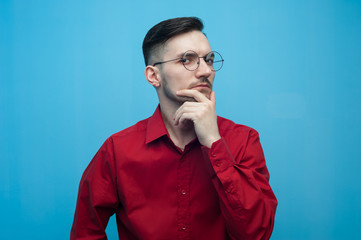 Pensive Young man in glasses and a burgundy shirt