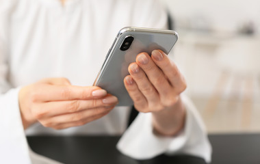 Young woman with mobile phone in office, closeup