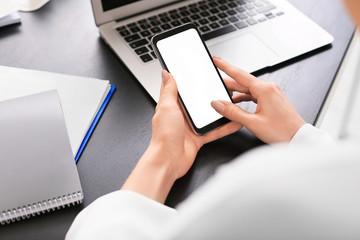 Young woman with mobile phone in office, closeup