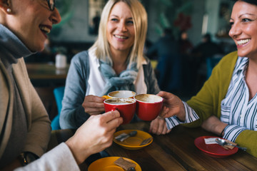 woman friends on coffee break at cafe, cheers with coffee