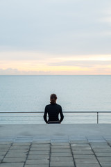 Mujer haciendo estiramientos mirando al mar en el amanecer