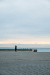 Hombre de espaldas caminando al amanecer con mar de fondo