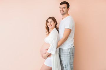 Beautiful pregnant couple on color background
