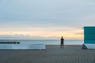 Hombre de espaldas caminando al amanecer con mar de fondo