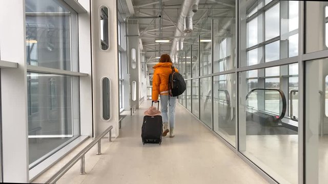 Woman with luggage going to airplane before a departure at the airport terminal. Video recorded on a smartphone