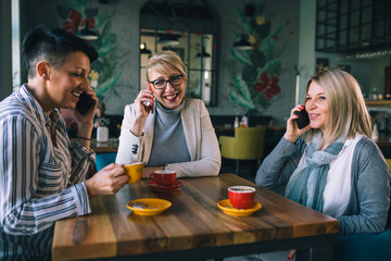woman friends on coffee break at cafe, using smartphone