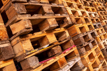 A lot stacks of used  wooden pallets of euro type on warehouse is ready for recycling. Industrial background. Close-up.