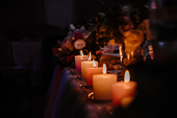 Romantic candles burn in the dark against the background of flowers