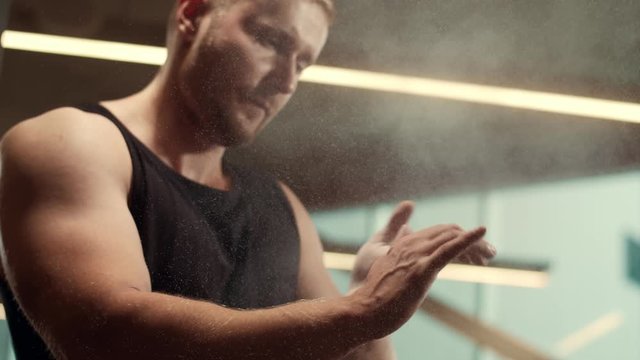 Athletic handsome male sportsman working in the gym using talcum powder. Strong and healthy bodybuilder abdominal training exercises. Sport, fitness, workout and lifestyle.