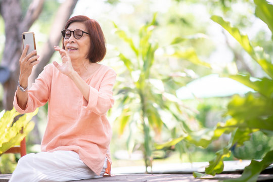 Asian senior woman at  the outdoor garden  using smart phone to taking picture or face to face call, face recognition,on line chat. technology communication concept