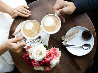 Hands of bride and groom with latte art coffee cup. Marriage concept