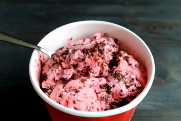 Spoon scooping tasty strawberry chocolate chunk ice cream with selective focus