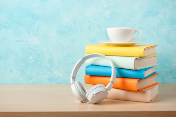 Headphones, stack of books and cup on a table