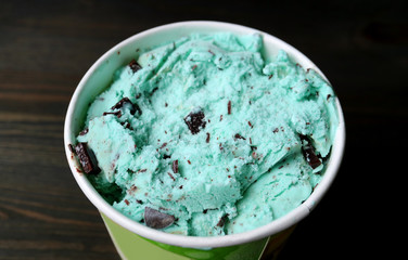 Closeup a Large Cup pf Mint Chocolate Chip Ice Cream on Dark Brown Wooden Table