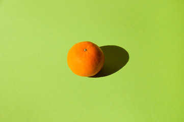 Juicy delicious tangerine on bright green background.