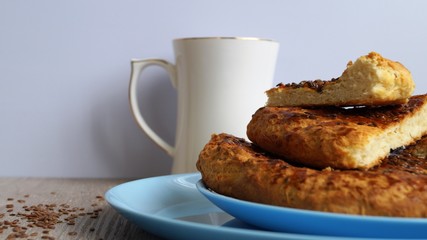 oriental bread on a blue dish with white porcelain mug and linen seeds on a wooden table on white background