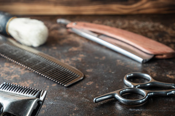 vintage barber tools: dangerous razor, hairdressing scissors, old manual clipper, metal comb, shaving brush.