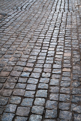 Dark cobbles. Stone pavement road. Street pavers glisten in the sun.