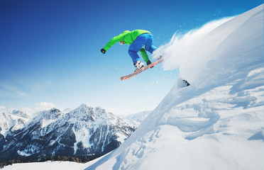 Jumping skier in alpen mountains. Freeride fun in fresh snow.