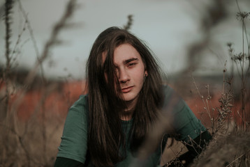 Long haired teenage boy with heterochromia in nature