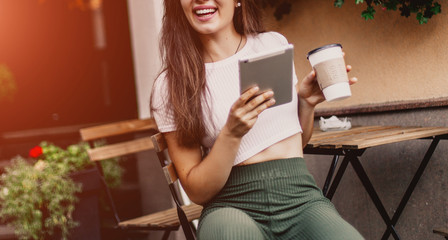 Beautiful woman using tablet and drink coffee sitting in street cafe.