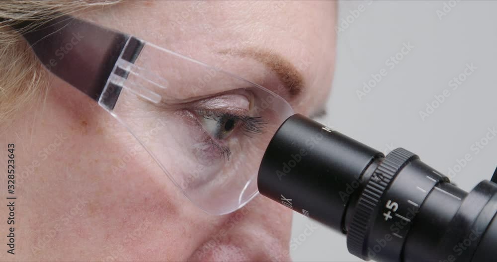 Wall mural close-up of woman scientist using microscope in a laboratory.