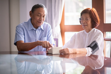 Fototapeta premium Asian retired couple operate home blood pressure monitoring