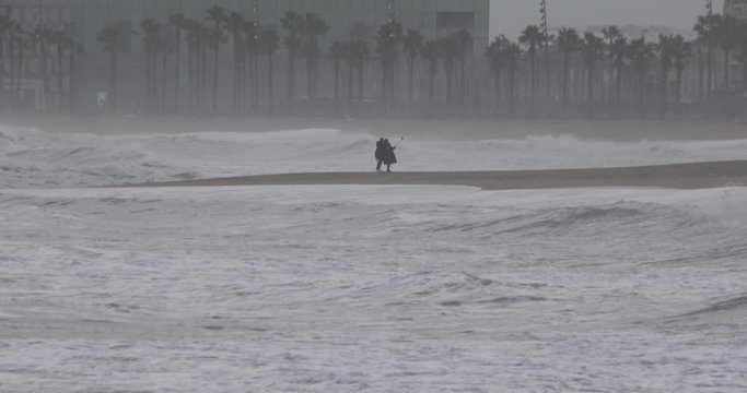 Long shot of people taking selfie picture with stick on a beach during rain and storm