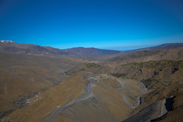 Fototapeta na wymiar Curvy road goes among the hills and mountains with clear blue sky background