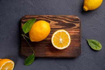 Juicy and ripe lemons with leaves on a dark background