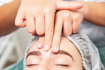 Massage of forehead of woman.