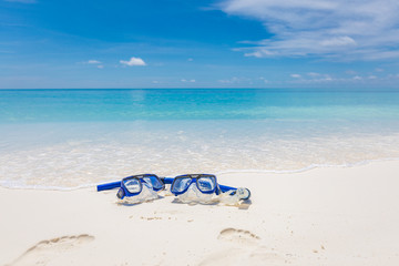 Summer sport, beach activity, beach recreational concept. Diving goggles and snorkel gear on white sand near beach. Summer vacation and recreational travel background