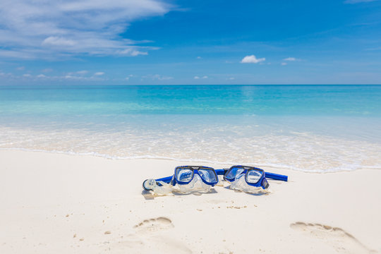 Summer sport, beach activity, beach recreational concept. Diving goggles and snorkel gear on white sand near beach. Summer vacation and recreational travel background