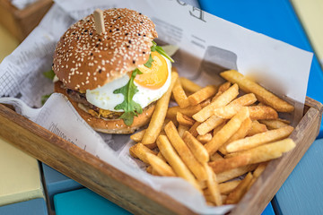 Tasty beef hamburger with fries in wooden box serving. Delicious gourmet food, special burger