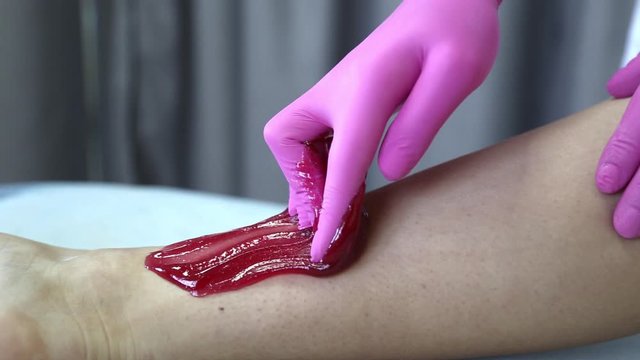 Removing unnecessary hair on the legs. Procedure sugaring in a beauty salon. Sugar depilation. Depilatory sugar paste
