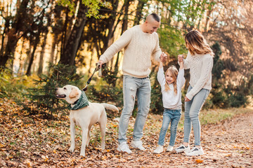 Fototapeta premium Happy beautiful family with dog labrador is having fun together walking the in park.