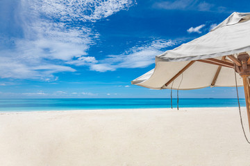 White umbrella on the beach. Parasol as summer vacation or holiday detail. Relaxation beach and tropical landscape concept. Sun umbrella under blue sky