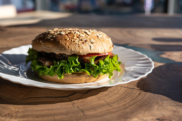 Big sandwich - hamburger with juicy chicken burger, cheese, tomato, and red onion on wooden background