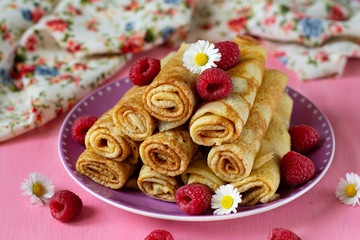 Stack of thin pancakes crepes served with raspberries