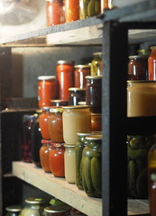 The benefits and harms of canned products. Domestic blanks in banks in the basement are arranged in a row on shelves for storage.