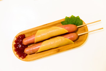 Antipasto platter boiled Frankfurter sausages with sauce on a wooden plate with cheese and mint...