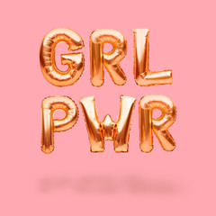 Naklejka premium Lettering GRL PWR or girl power made of golden inflatable helium balloons on pink background. Gold foil balloon font forming abbreviation for the feminist slogan. Party decorations.