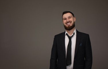 Portrait of a handsome bearded man smiling against grey background with copy space.