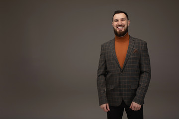 Obraz premium Young brunette businessman, with beard, wearing in suit on gray background