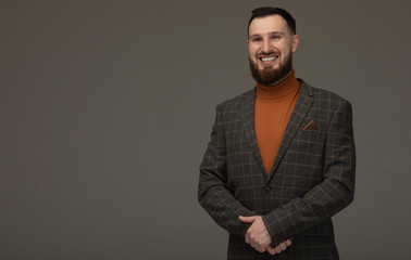 Obraz premium Handsome young bearded man on grey background looking at camera. Portrait of laughing young man.