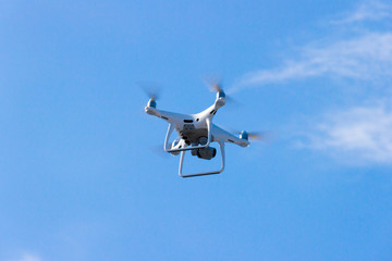 Quadcopter drone is flying in the blue sky. Unmanned aerial vehicle. Remote video shooting from a height. Modern digital camera